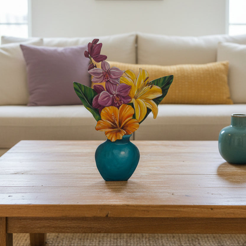 A decorative painted floral arrangement in a blue vase, featuring purple orchids, yellow lilies, and orange hibiscus flowers with green leaves, displayed on a wooden table in front of a beige cushioned sofa.
